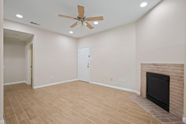 unfurnished living room with ceiling fan, a brick fireplace, and light wood-type flooring