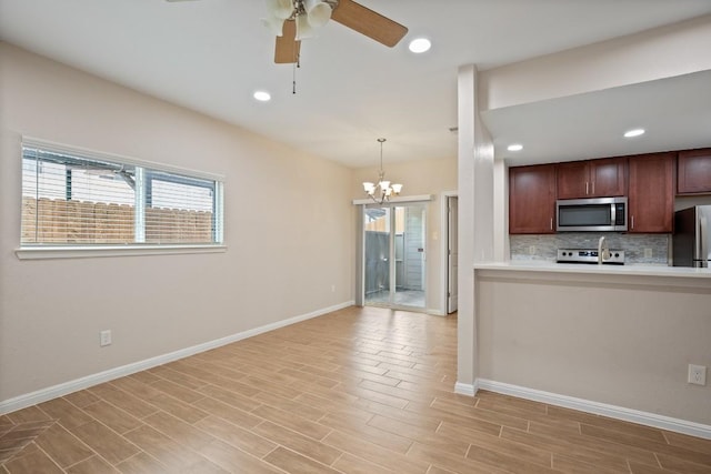 kitchen with pendant lighting, light hardwood / wood-style flooring, appliances with stainless steel finishes, tasteful backsplash, and ceiling fan with notable chandelier