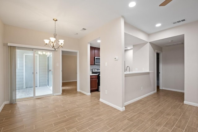 interior space featuring decorative light fixtures, light wood-type flooring, stainless steel appliances, ceiling fan with notable chandelier, and backsplash