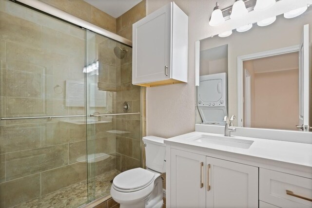 bathroom featuring stacked washer and dryer, vanity, toilet, and an enclosed shower