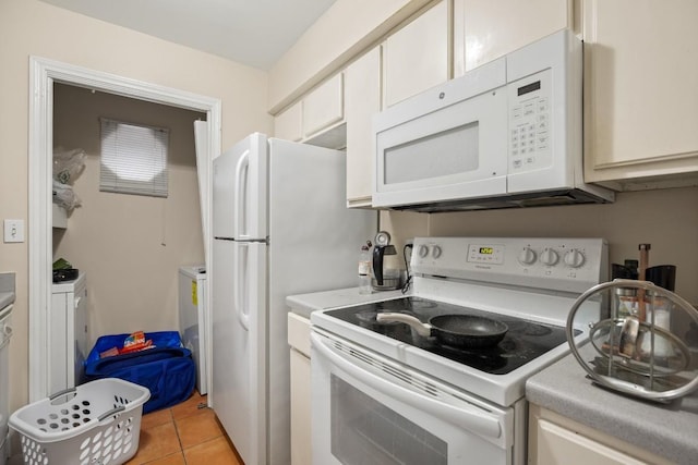 kitchen featuring white appliances, separate washer and dryer, light tile patterned floors, and white cabinets