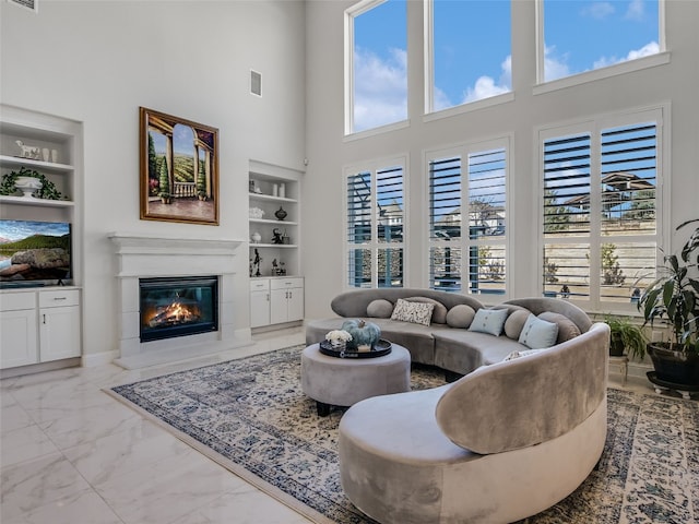 living room with a healthy amount of sunlight, built in features, and a towering ceiling