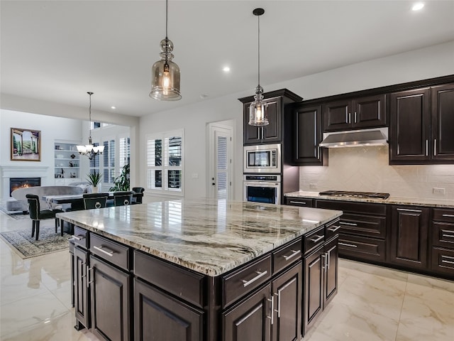 kitchen featuring dark brown cabinetry, tasteful backsplash, a center island, pendant lighting, and stainless steel appliances