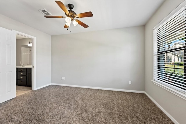 unfurnished bedroom featuring light carpet, ensuite bath, and ceiling fan