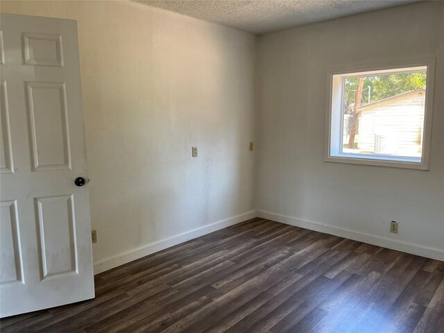1207 NE Loop 230th Loop, Smithville, TX 78957 - empty room with dark wood-style floors, baseboards, and a textured ceiling