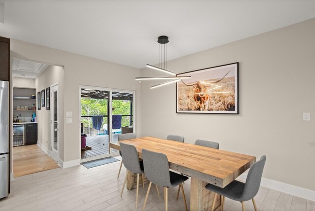 dining room with bar area, beverage cooler, and light hardwood / wood-style floors