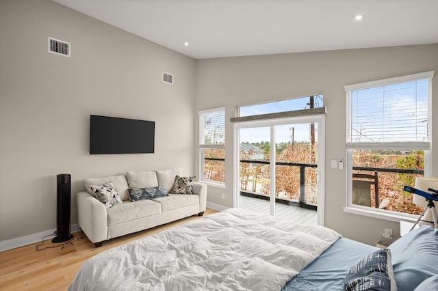 bedroom with multiple windows, lofted ceiling, and light wood-type flooring