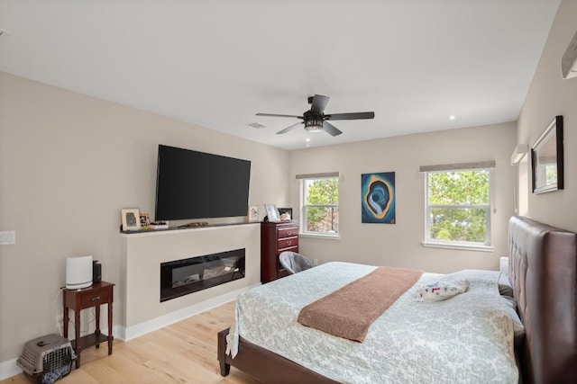 209 Kipahulu Dr, Bastrop, TX 78602 - bedroom featuring wood finished floors, a glass covered fireplace, and ceiling fan