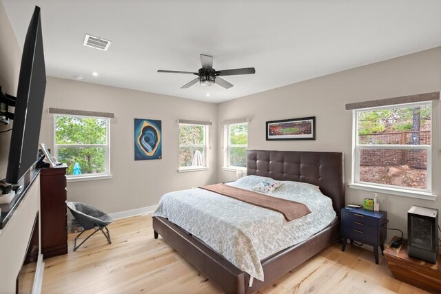 bedroom with ceiling fan, multiple windows, and light hardwood / wood-style flooring