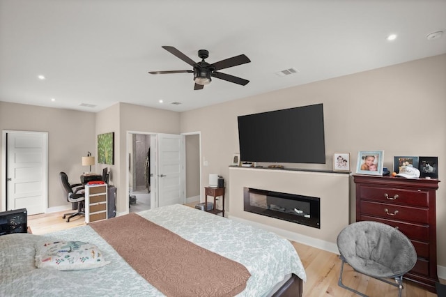 209 Kipahulu Dr, Bastrop, TX 78602 - bedroom featuring wood finished floors, recessed lighting, a glass covered fireplace, a ceiling fan, and an office area