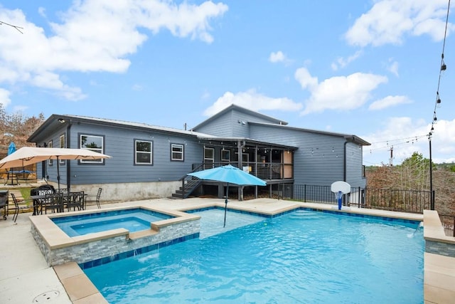 view of pool with a patio, a sunroom, stairs, fence, and a pool with connected hot tub