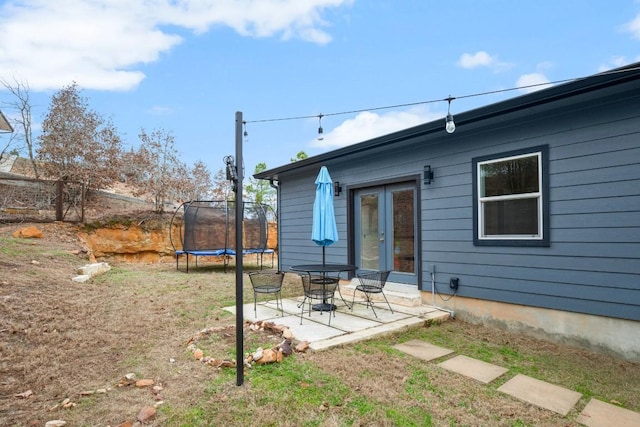 view of yard with a trampoline, french doors, and a patio area