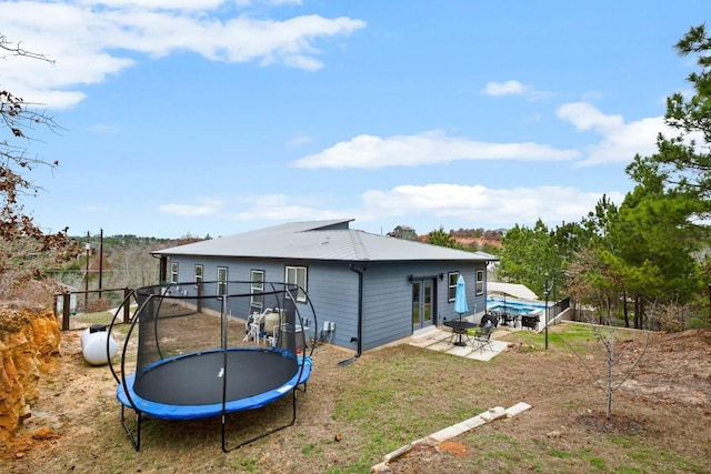 209 Kipahulu Dr, Bastrop, TX 78602 - back of property featuring a trampoline, a patio, a metal roof, a yard, and french doors
