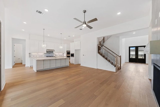 7605 Becasseau Dr, Austin, TX 78738 - unfurnished living room with a ceiling fan, recessed lighting, light wood finished floors, visible vents, and stairs