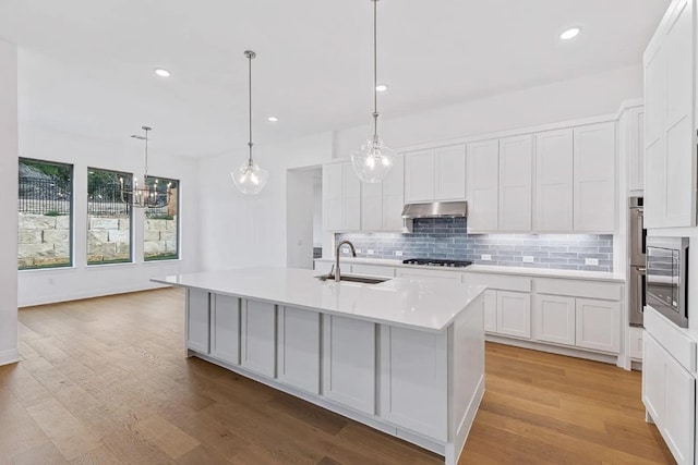 7605 Becasseau Dr, Austin, TX 78738 - kitchen with gas stovetop, a sink, white cabinetry, light countertops, and decorative backsplash