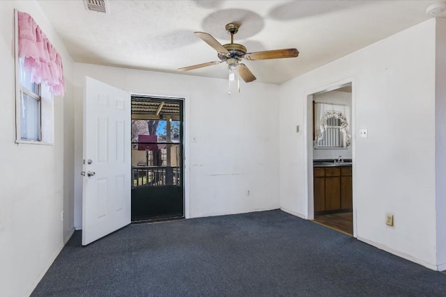 unfurnished room featuring dark colored carpet and ceiling fan