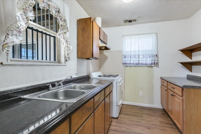 kitchen featuring hardwood / wood-style floors, sink, white range with gas stovetop, and a textured ceiling