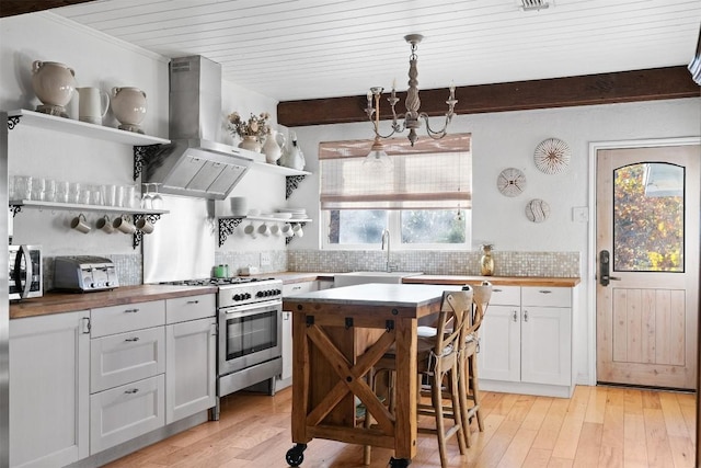 kitchen featuring pendant lighting, white cabinetry, high end stove, and wooden counters