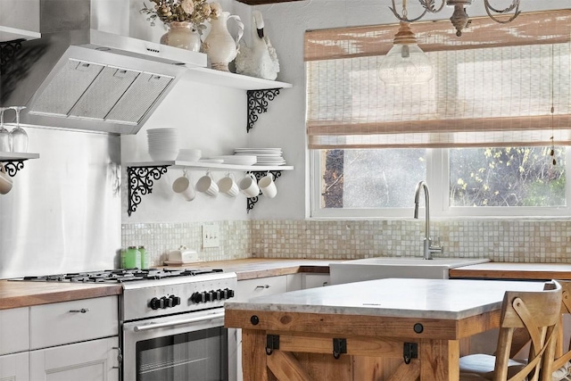 kitchen featuring sink, white cabinets, backsplash, high end stainless steel range oven, and wall chimney exhaust hood