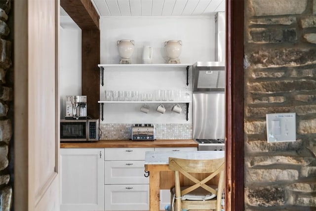 bar featuring butcher block counters, white cabinetry, ornamental molding, stainless steel appliances, and decorative backsplash