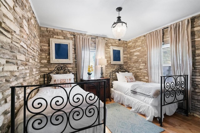 bedroom featuring a notable chandelier, ornamental molding, multiple windows, and light hardwood / wood-style flooring