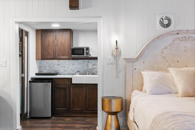 bedroom with dark hardwood / wood-style floors, sink, and refrigerator