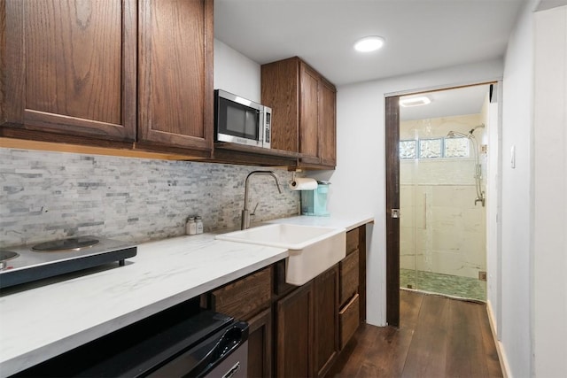 kitchen with tasteful backsplash, dishwasher, sink, and dark hardwood / wood-style flooring