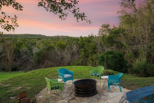 patio terrace at dusk with a fire pit and a lawn