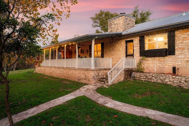 back house at dusk featuring a lawn