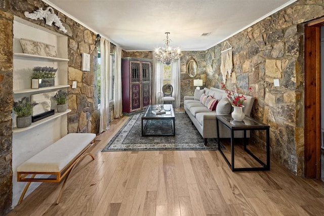 living room featuring hardwood / wood-style flooring, crown molding, and a notable chandelier