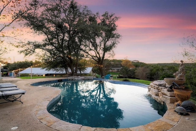 pool at dusk with a patio