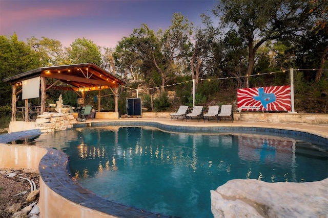 pool at dusk featuring a gazebo