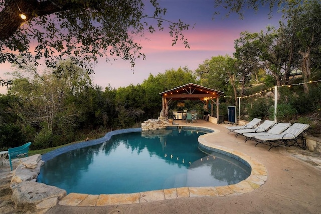 pool at dusk with a gazebo and a patio