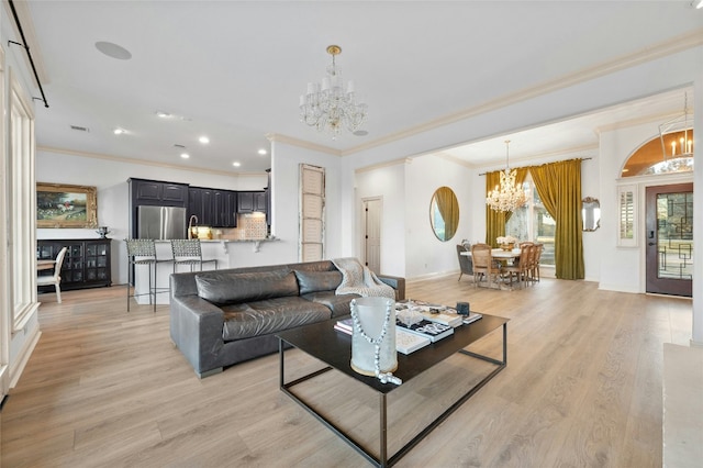 living room featuring an inviting chandelier, ornamental molding, and light hardwood / wood-style flooring