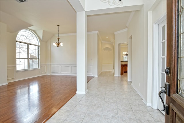 foyer entrance featuring crown molding, light tile patterned floors, and an inviting chandelier