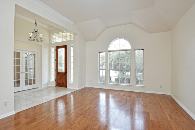 entrance foyer with an inviting chandelier, lofted ceiling, french doors, and light wood-type flooring