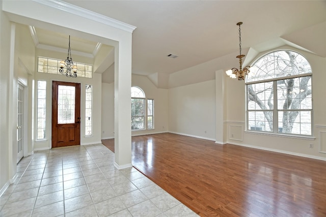 entrance foyer with an inviting chandelier, ornamental molding, and light wood-type flooring