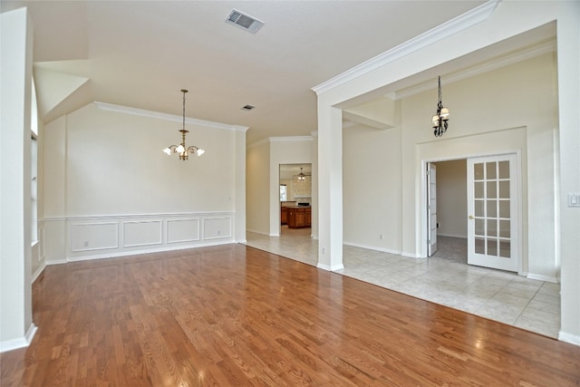 empty room featuring ornamental molding, a notable chandelier, and light hardwood / wood-style flooring