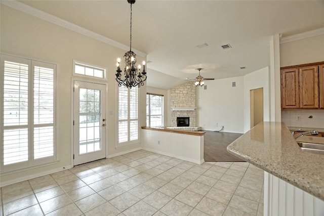 kitchen featuring sink, hanging light fixtures, tasteful backsplash, light stone countertops, and a stone fireplace