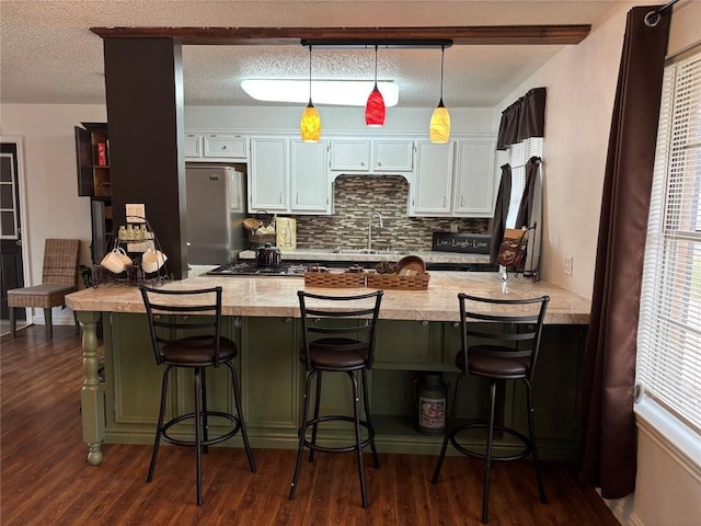 kitchen with pendant lighting, a breakfast bar area, appliances with stainless steel finishes, white cabinetry, and dark hardwood / wood-style floors