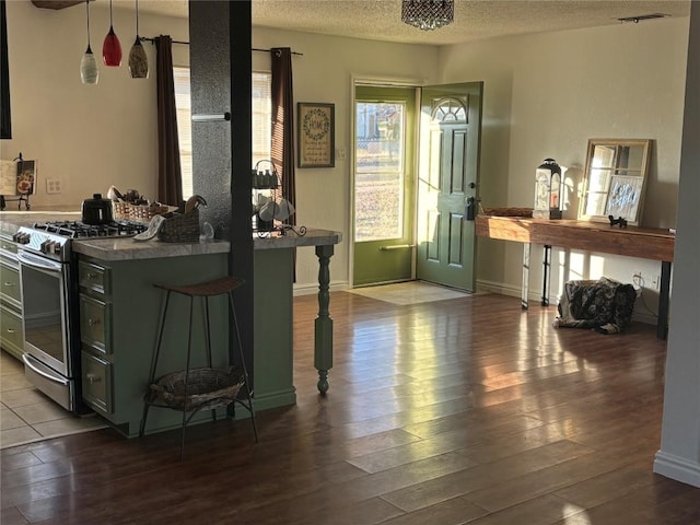 kitchen featuring stainless steel gas stove, hardwood / wood-style floors, a kitchen breakfast bar, and a textured ceiling