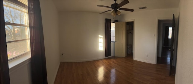 unfurnished room with ceiling fan, a healthy amount of sunlight, and dark hardwood / wood-style flooring