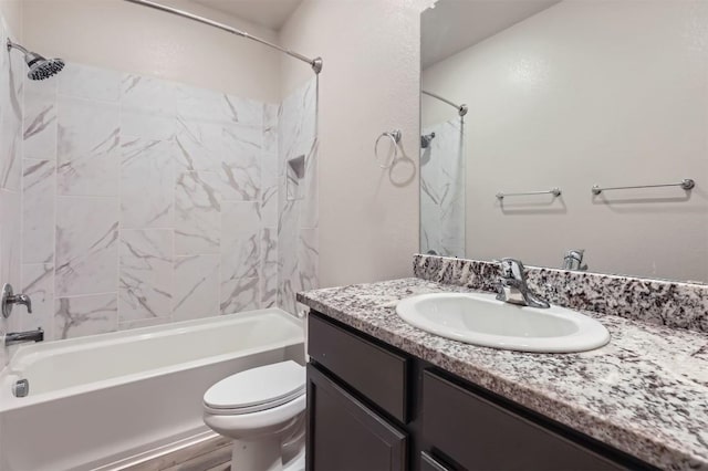 full bathroom featuring vanity, tiled shower / bath, and toilet