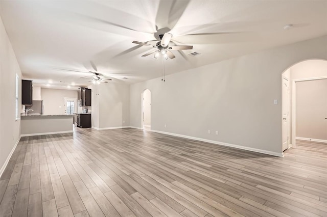 unfurnished living room featuring sink, light hardwood / wood-style floors, and ceiling fan