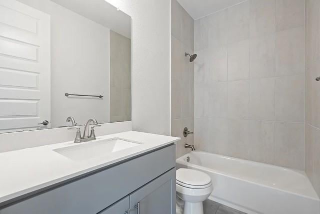 full bathroom featuring vanity, tiled shower / bath combo, and toilet