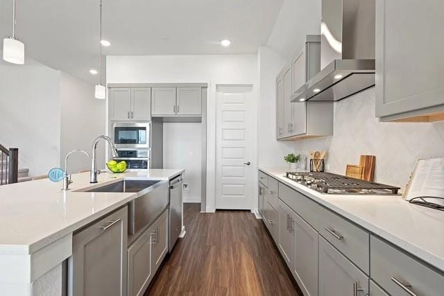 kitchen featuring gray cabinetry, appliances with stainless steel finishes, dark hardwood / wood-style flooring, pendant lighting, and wall chimney range hood