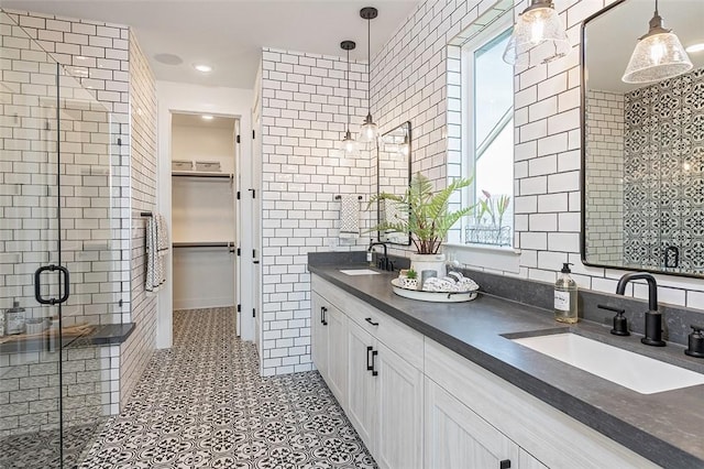 bathroom with tile patterned flooring, vanity, a shower with shower door, and tile walls