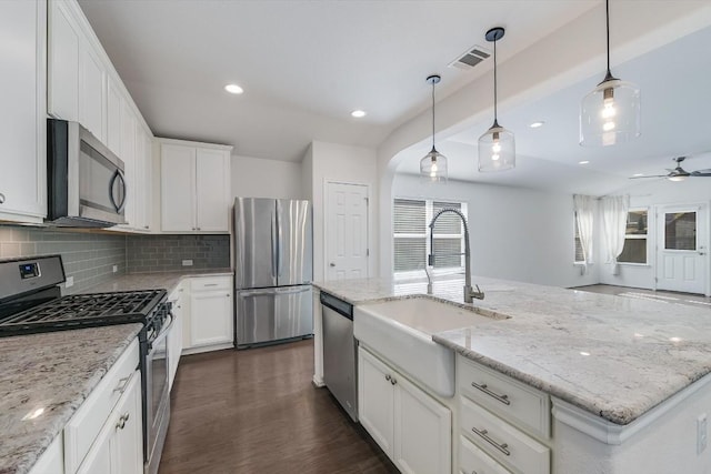 kitchen with sink, decorative light fixtures, a center island with sink, appliances with stainless steel finishes, and white cabinets