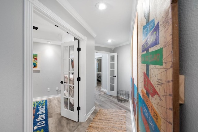 corridor with crown molding, light wood-type flooring, and french doors