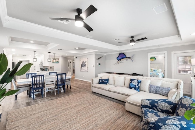 living room featuring hardwood / wood-style flooring, crown molding, and a raised ceiling